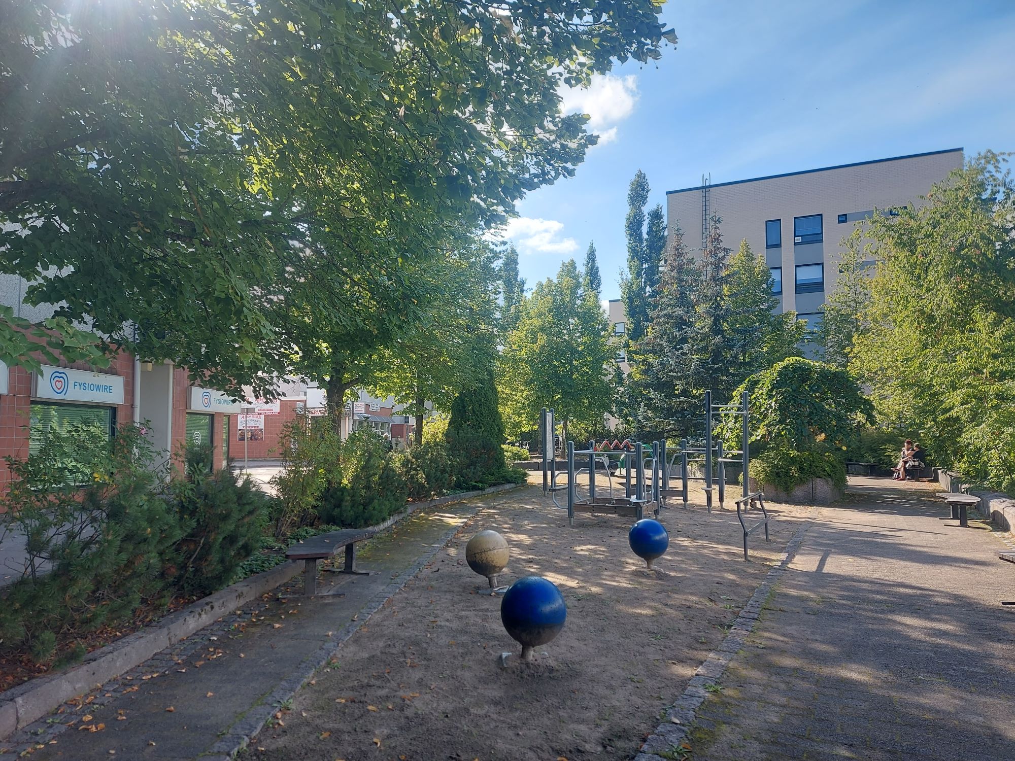 Kölhinpuisto, jossa puistotelineitä, ympärillä puita ja kerrostaloja.